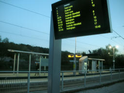 A tram and bus departure display, with the tram platforms behind